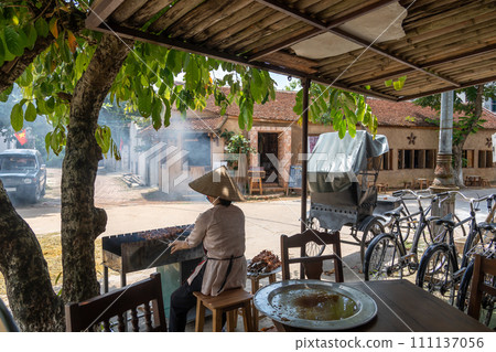 A woman grilling yakitori in front of a restaurant in Dong Lam village, designated as a national cultural property in Hanoi, Vietnam 111137056