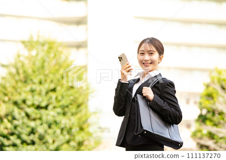 Young woman in a business suit holding a smartphone Young woman in a business suit holding a smartphone 111137270