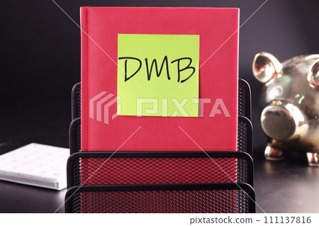 DMB text on a yellow sticker pasted on an upright diary on a black background 111137816