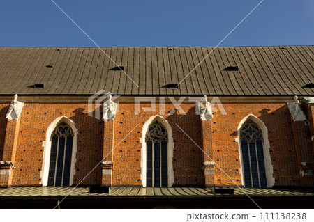 Large decorative church windows with stained glass. Fragment of the wall and stained glass windows of the Catholic Church in the old town of Krakow, Poland. 111138238