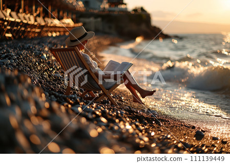 A mature woman sits on a sun lounger by the sea and reads a book A mature woman sits on a sun lounger by the sea and reads a book 111139449