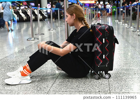Sad (tired) woman sitting in the airport - missed or cancelled flight concept. Sad (tired) woman sitting in the airport - missed or cancelled flight concept. 111139965