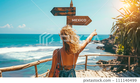 Sign pointing to the direction of Mexico with scenic beach and ocean in the background 111140499