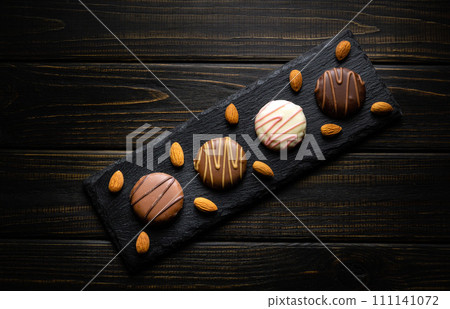 Round chocolate chip cookie on a black serving board and nuts. Delicious dessert concept on vintage dark kitchen table 111141072