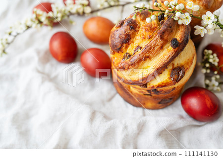 A traditional Easter bread with painted eggs and blossoms on a textured fabric. Festive, colorful, and appetizing. 111141130