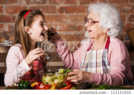 Granny gives to try a tasty vegetable salad to her grandchild 111141838