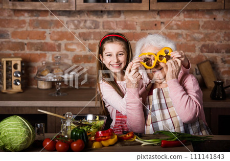 Grandchild with granny having fun while cooking at home 111141843