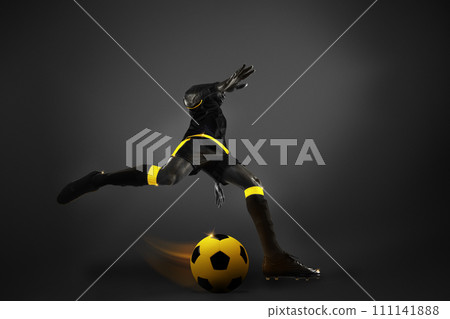 Bottom view. Competitive man, soccer athlete ion motion during game, playing over dark background. Yellow elements. Monochrome Bottom view. Competitive man, soccer athlete ion motion during game, playing over dark background. Yellow elements. Monochrome 111141888
