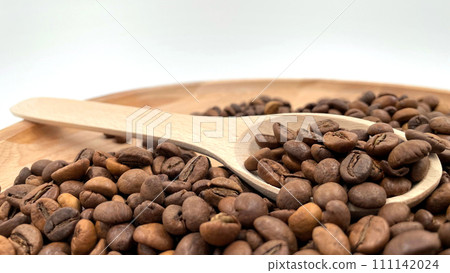 Food background texture of roasted coffee beans with a full shovel. A pile of scattered aromatic roasted brown coffee beans with a wooden scoop. Coffee beans in a wooden spoon 111142024