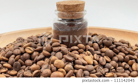Coffee beans ground in a coffee grinder, mortar or mill in a small glass jar on the table. Coarse or medium grind are packed for storage. A drink made from roasted and ground grains Coffee beans ground in a coffee grinder, mortar or mill in a small glass jar on the table. Coarse or medium grind are packed for storage. A drink made from roasted and ground grains 111142045
