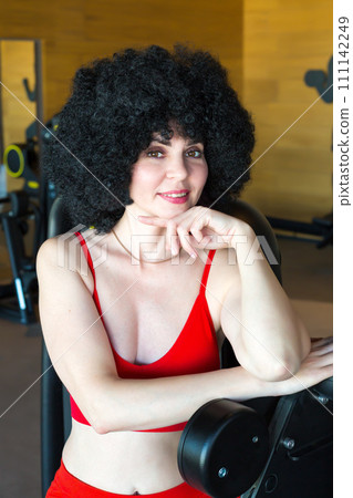 A beautiful slender brunette stands near the equipment in the gym 111142249