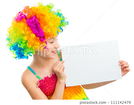 Young little girl in colourful clown wig holding white blank sheet of paper isolated on white background, copyspace 111142479
