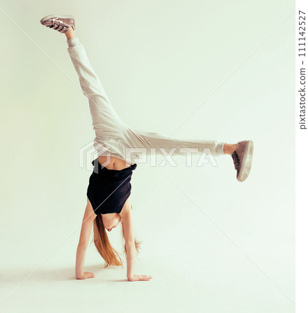 Attractive flexible teenage girl doing handstand on light background Attractive flexible teenage girl doing handstand on light background 111142527
