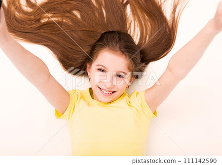 Lovely long haired girl lying on the floor, stretching and reaching up, smiling Lovely long haired girl lying on the floor, stretching and reaching up, smiling 111142590