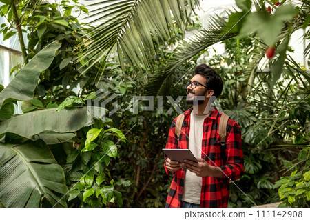 Dark-haired hindu man with backpack walking in botanical garden 111142908