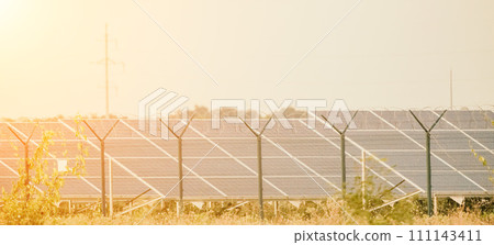 Large solar station with blue photovoltaic panels fenced with lattice and barbed wire. Producing clean energy from the sun and minimizing the carbon footprint. 111143411