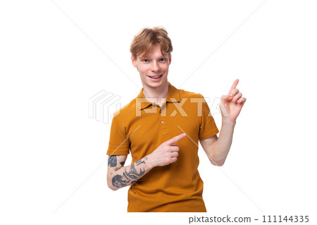 a young guy with short red hair dressed in a summer T-shirt points to the side with his hand a young guy with short red hair dressed in a summer T-shirt points to the side with his hand 111144335