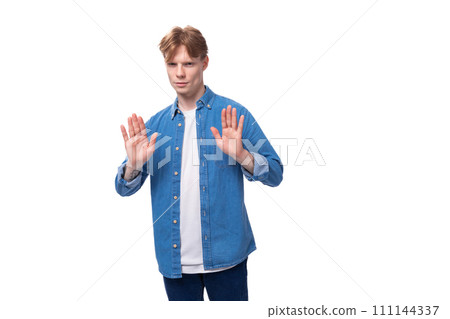 young well-groomed caucasian red-haired man in a denim shirt actively gesticulates 111144337