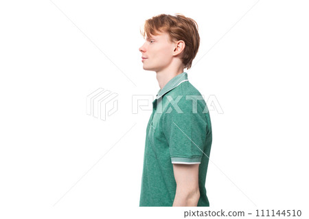 a young European guy with red hair in a green T-shirt stands in profile a young European guy with red hair in a green T-shirt stands in profile 111144510