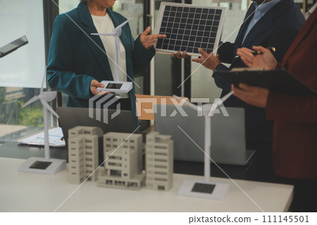 Close-up at tablet, Engineers pointing at tablet with their hands. To jointly design the use of renewable energy with wind and solar energy. Concept of using renewable energy. 111145501