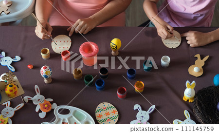 High angle view of family painting wooden Easter eggs while sitting at table 111145759