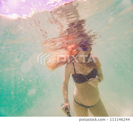 In an ethereal underwater scene, a pregnant woman gracefully floats, embodying the beauty of maternity beneath the tranquil surface of the sea In an ethereal underwater scene, a pregnant woman gracefully floats, embodying the beauty of maternity beneath the tranquil surface of the sea 111146244