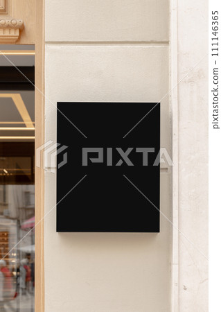 Wall-mounted black signboard on a textured wall, ideal for businesses to display their brand logo or promotional content. Black signage mockup. 111146365
