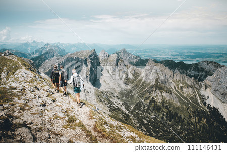 Three Hikers on a hiking trail on Hochplatte Mountan in the Ammergau Alps Three Hikers on a hiking trail on Hochplatte Mountan in the Ammergau Alps 111146431