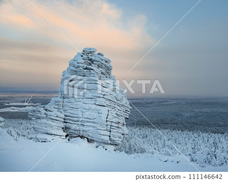 Big granite rock is frozen and covered with snow. Natural stone Big granite rock is frozen and covered with snow. Natural stone 111146642