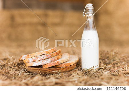 Milk bottle and slices of fresh wheat bread on hay Milk bottle and slices of fresh wheat bread on hay 111146708