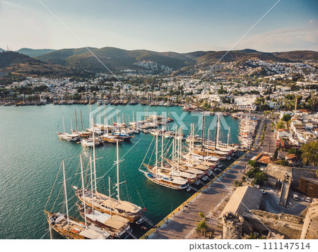 Bodrum Cruise Port southwestern Aegean sea harbor. A stunning view of sailing yachts in Port. Yachts in sunset bay. Sailing boats sunset scene. Sunset yachts view.  111147514