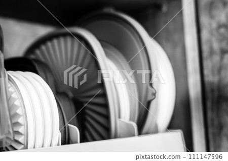 Narrow depth of field picture of an open kitchen cabinet with rows of organized storage of plastic lids. Narrow depth of field picture of an open kitchen cabinet with rows of organized storage of plastic lids. 111147596