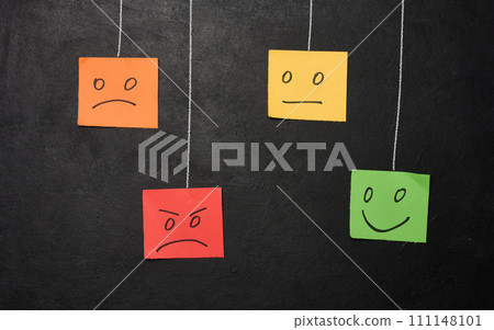 Drawn faces with different emotions on a sticker and attached to a chalkboard. 111148101