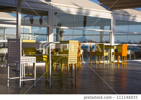 Summer cafe with colorful wicker chairs and a large terrace with a glass facade, eating in fresh air 111148835