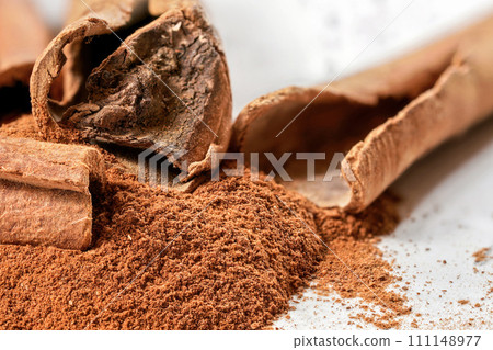 Closeup detail - Organic cinnamon bark stick and pile of grounded powder Closeup detail - Organic cinnamon bark stick and pile of grounded powder 111148977