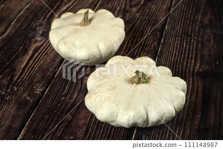 Two white pattypan squash on dark wooden board Two white pattypan squash on dark wooden board 111148987