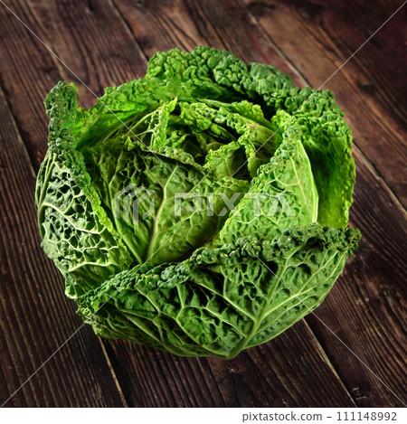 Single green savoy cabbage lettuce head on dark wooden board 111148992