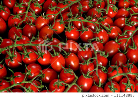 Group of small cherry tomatoes with green stems, top down view 111148993