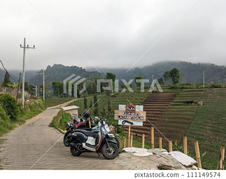The road is in the middle of forests and mountains which are cloudy and cool 111149574