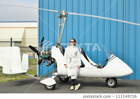 A woman near two-seater white gyrocopter A woman near two-seater white gyrocopter 111149726