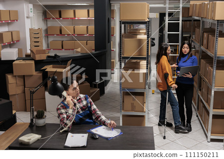 Delivery operators managing warehouse product audit in storage room. Retail industry storehouse employees working together, tracking parcel transportation online on laptop Delivery operators managing warehouse product audit in storage room. Retail industry storehouse employees working together, tracking parcel transportation online on laptop 111150211
