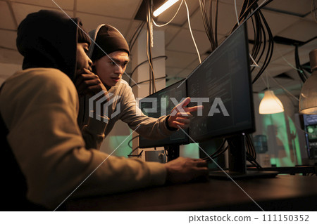 Hackers discussing computer system hacking, coding malicious software, cybercrime. Criminals planning cyberattack, programming internet virus, stealing data at night time 111150352