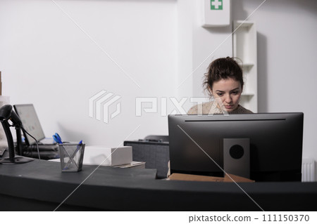 Storehouse supervisor standing at counter desk, analyzing merchandise logistics on computer. Storage room employee checking customers online orders preparing packages for delivery 111150370