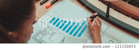 Close up of woman analyst working with financial statement graphic and making notes in coworking 111150853