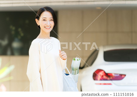 Woman with shopping bags in front of her home 111151016