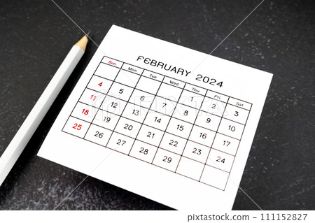 White calendar page for February 2024 and pencil on black. White calendar page for February 2024 and pencil on black. 111152827