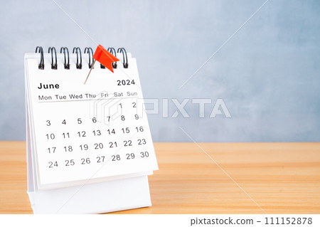 June 2024 calendar and red push pin on table. 111152878
