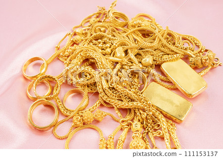 Many gold necklaces and gold bars on pink fabric background. Many gold necklaces and gold bars on pink fabric background. 111153137