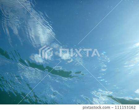 Looking through ocean water at blue sky and clouds with water ripples Looking through ocean water at blue sky and clouds with water ripples 111153162