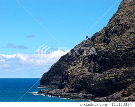 Makapu'u Lighthouse on cliffside mountain top with stretching blue pacific ocean below 111153324
